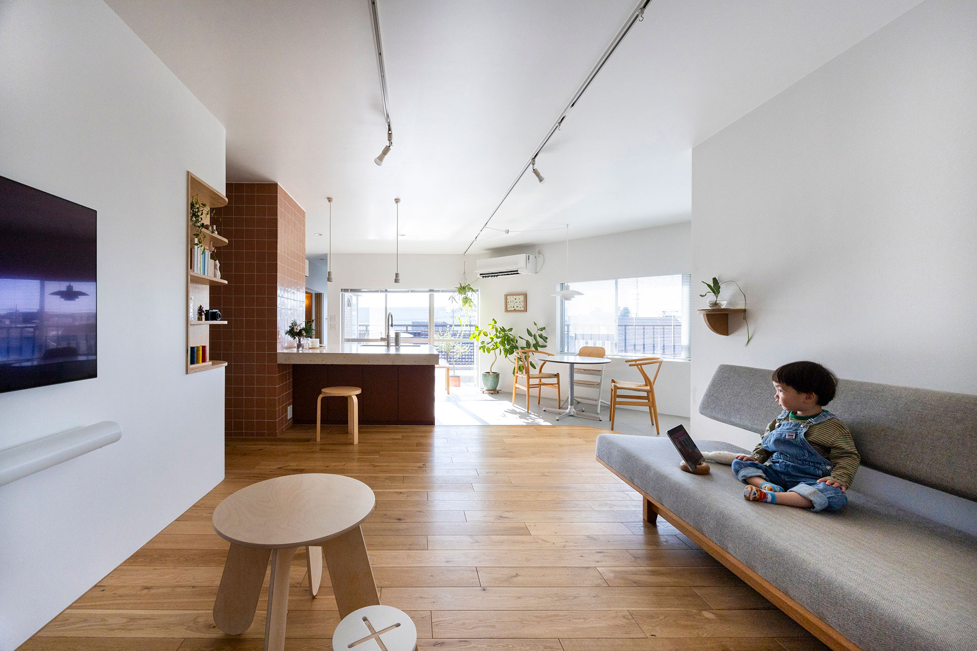 壁と天井は白く塗装。広々としたLDKに、三方の窓から日が入る。無垢のオーク材は、あえてフシが多く出ている素材を選んだ。