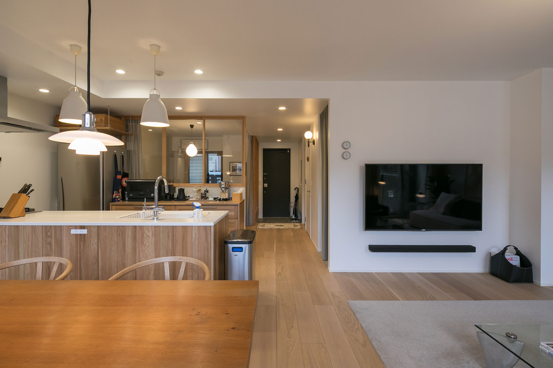 ダイニングから玄関方向を見る。キッチン背面のガラス戸越しに寝室に光が入る。