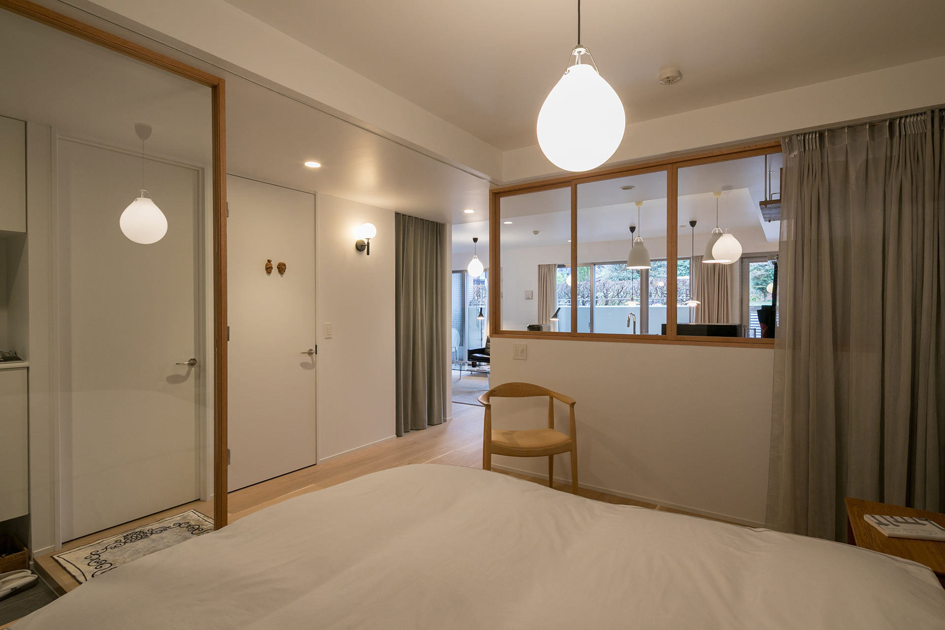 寝室から廊下とLDKを見る。左手のドアが書斎、隣のドアがトイレに続く。カーテンの奥は洗面・バスルーム。