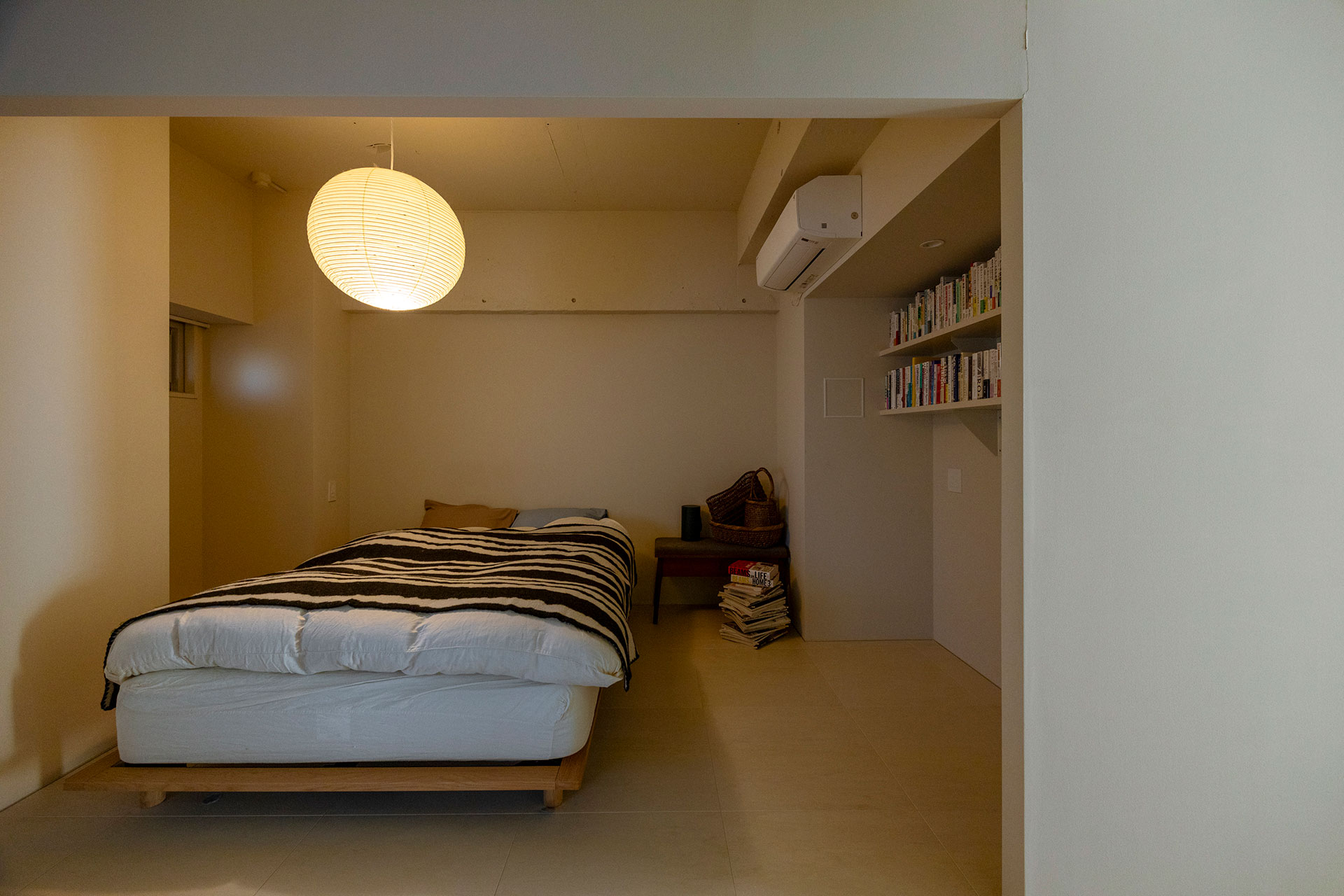 ベッドルームはオープンにしつつ、カーテンがかけられるようレールも設けた。イサム・ノグチのAKARIで月を、ミナペルホネンのベッドカバーのデザインで川を表現している。本棚下をワークスペースにする予定。