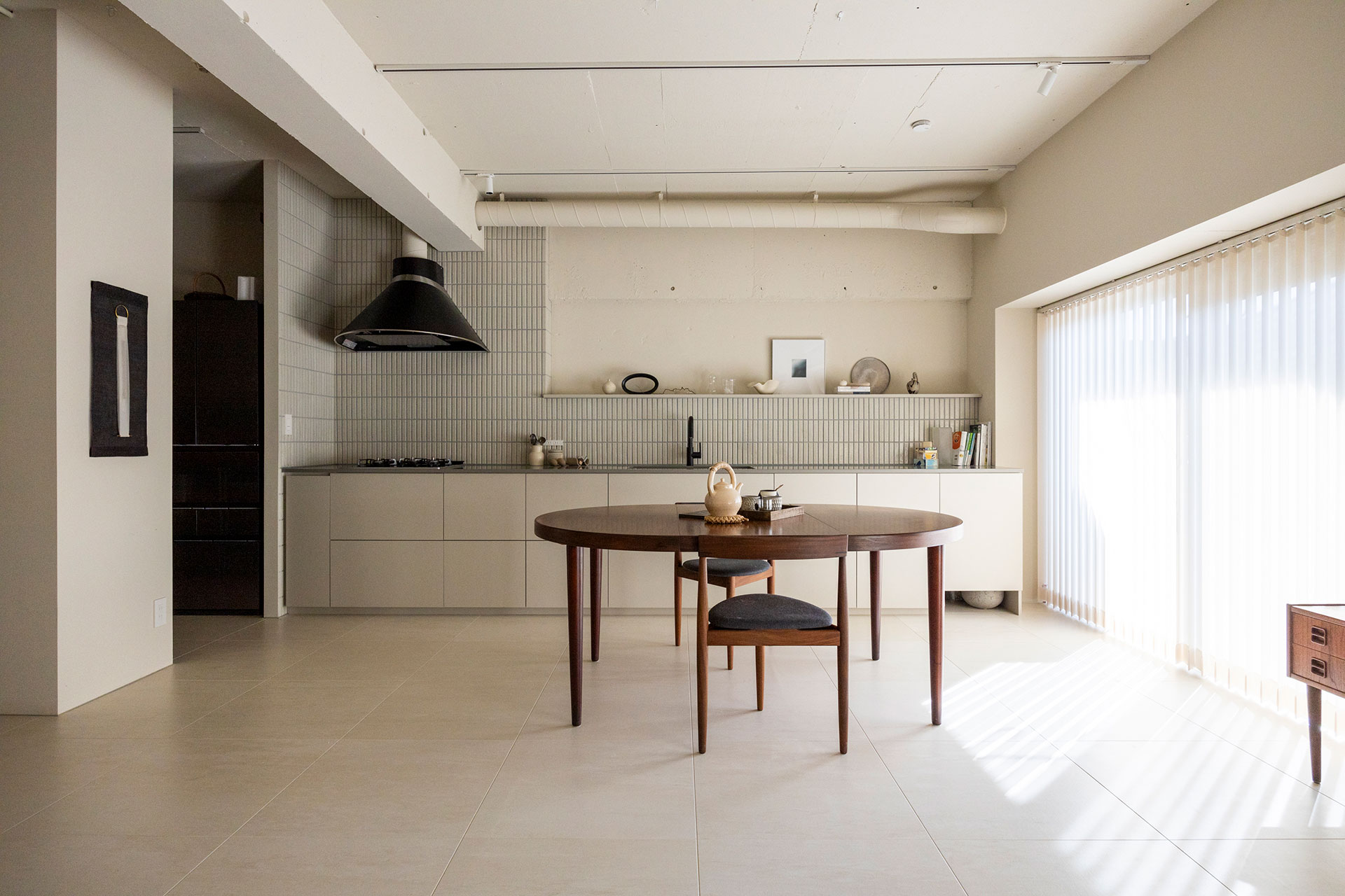 空間を広く取るため、キッチンは壁付けに。壁面をタイル貼りとコンクリートの躯体現しで対比させた。