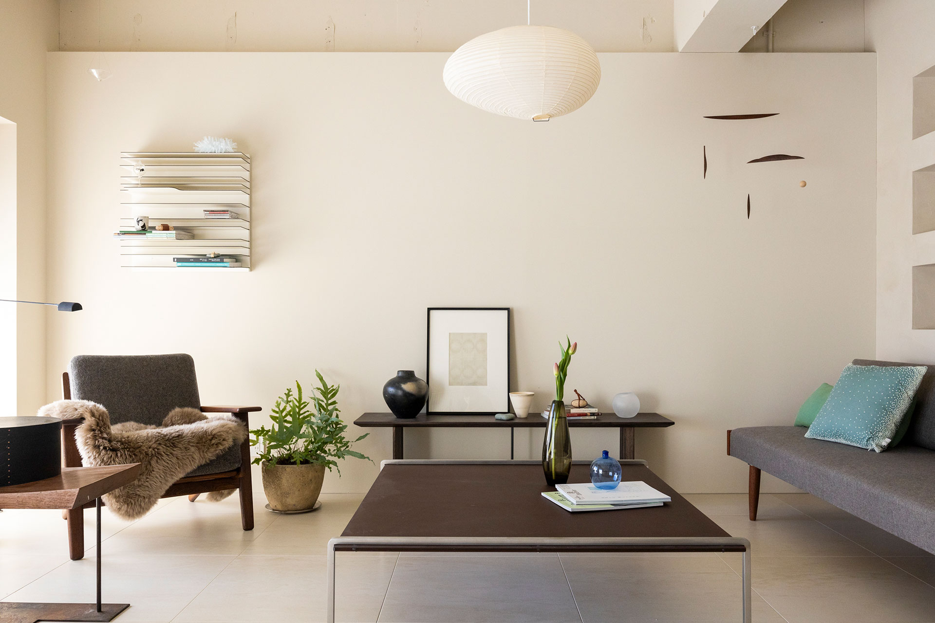 リビング側の壁面も、天井下を掘り込みにして、躯体を現している。ソファテーブルはコンスタンチン・グルチッチ。照明はAKARI。