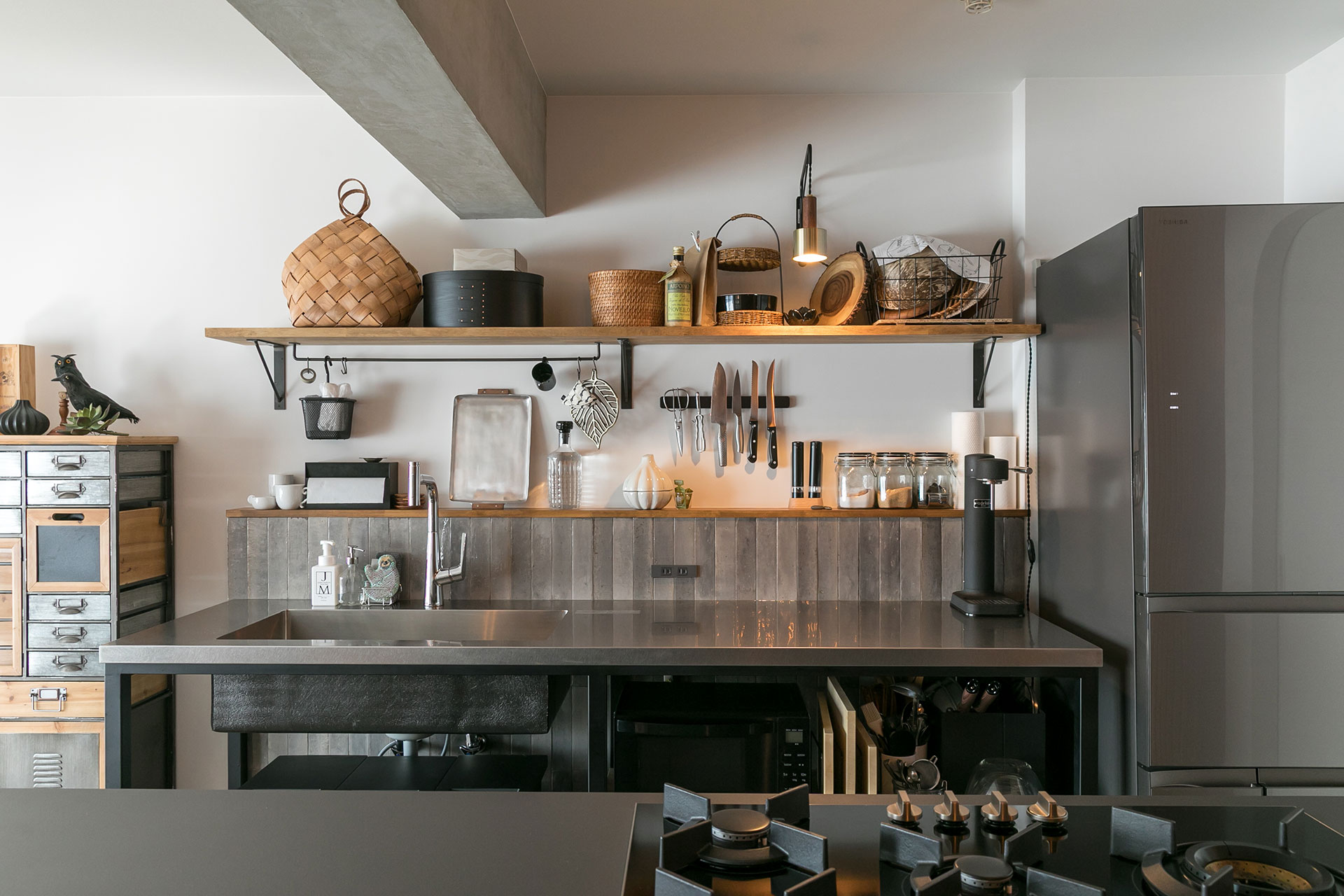 一枚一枚が違う表情がある点が気に入り採用した艶のあるタイル壁が、キッチンをインダストリアルすぎない空間にする。