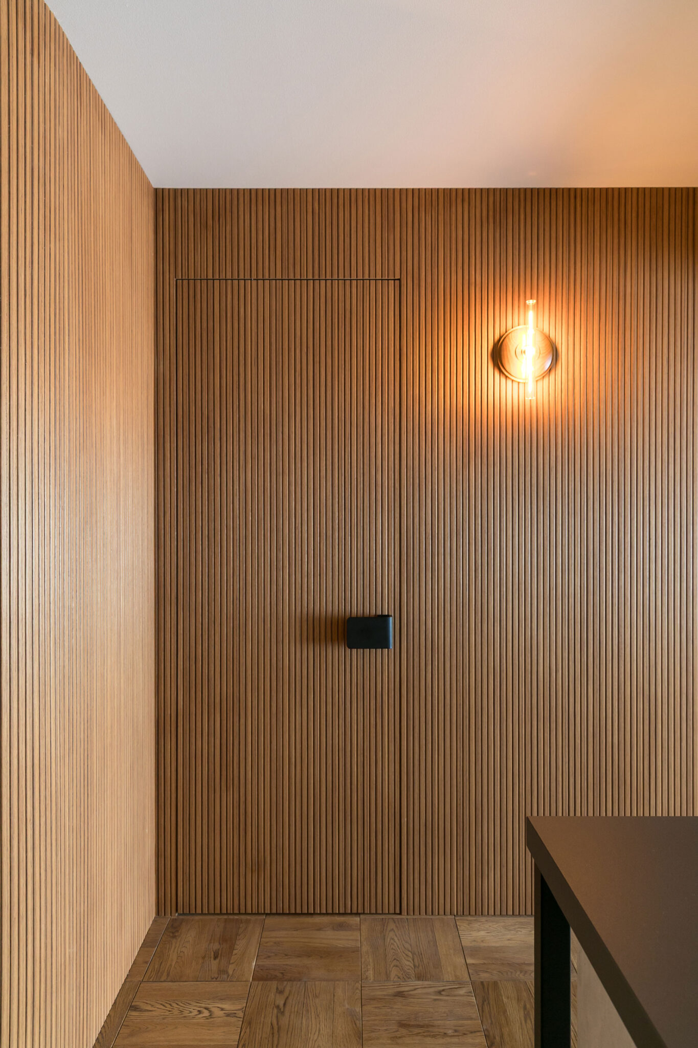 存在感のあるリブパネルの壁。ウォークインクローゼットへつながる扉のドアノブもアクセントカラーである黒を使っている。