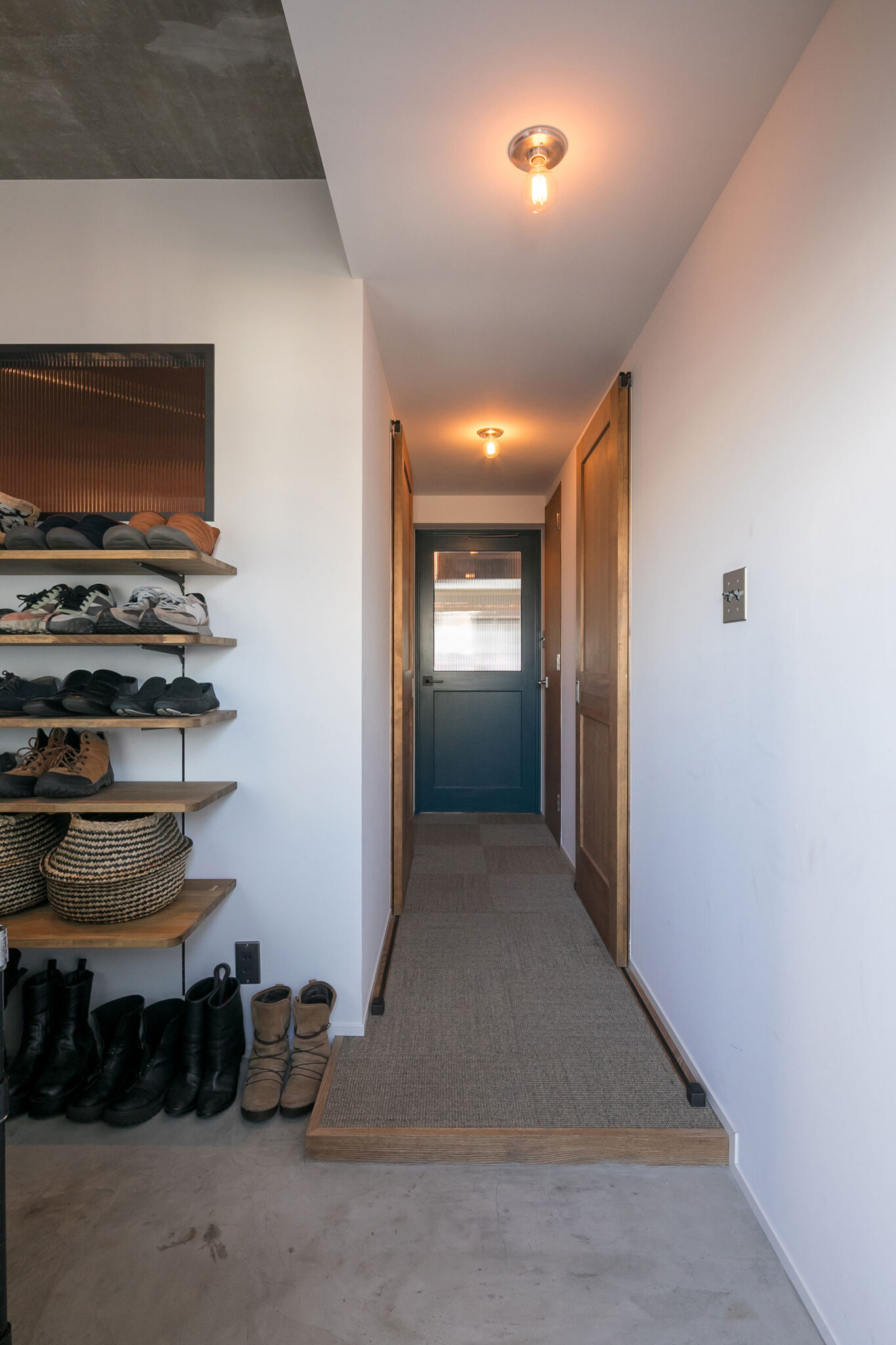 玄関の床材はモルタル。廊下までのアプローチが長く、アウトドアワゴンも楽々と通る。