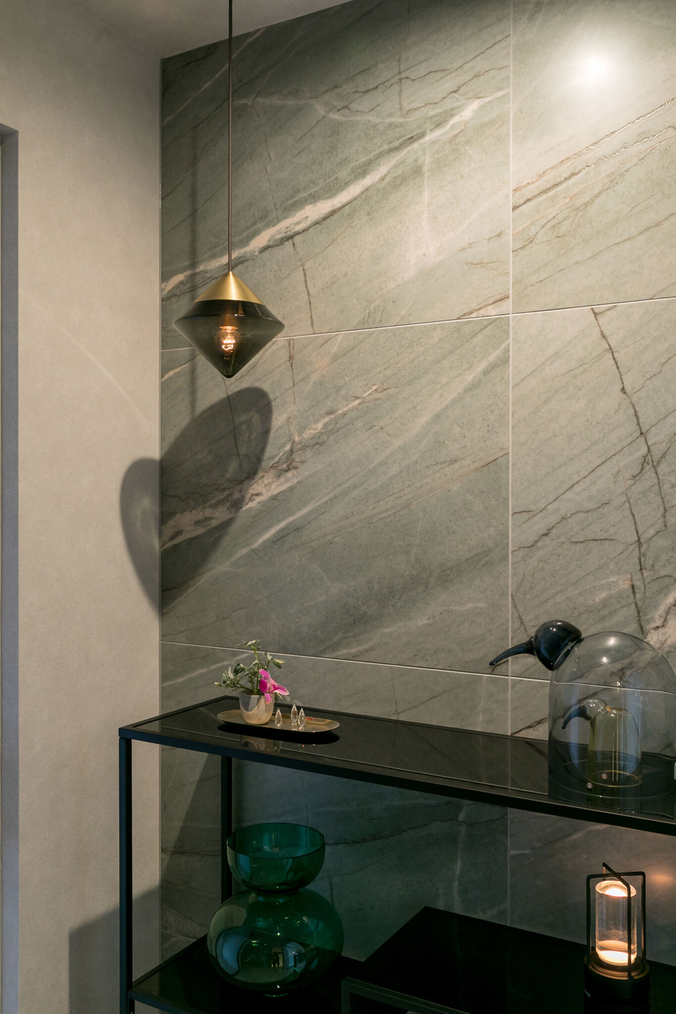 ホールのペンダントライトにはNEW LIGHT POTTERYの照明を採用。住まい全体のトーンをベージュで統一する一方、ホールの壁面にはグリーンの大判タイルを用い、空間にさりげないアクセントを与えている。