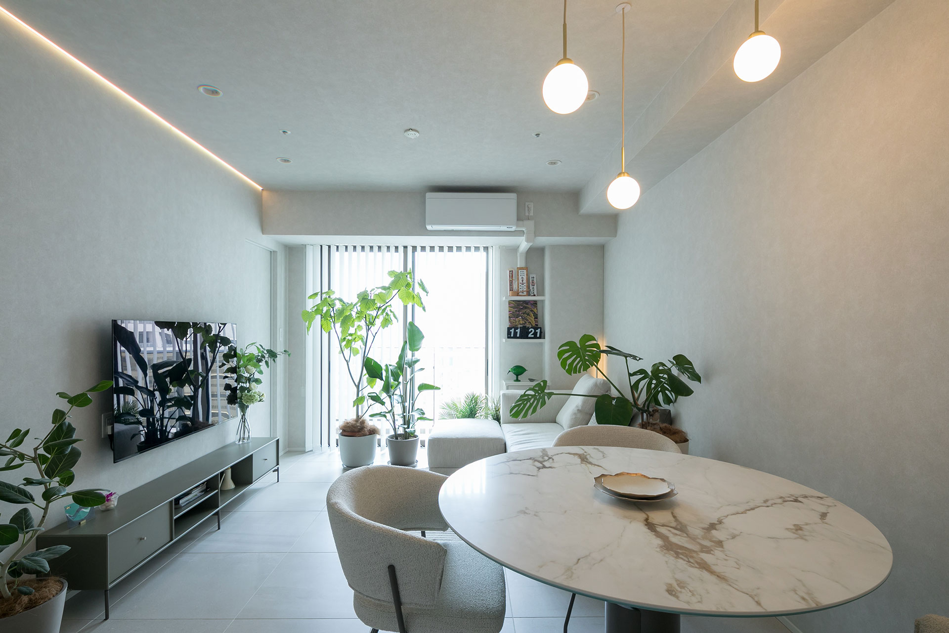 キッチンからリビング・ダイニングを見る。壁付テレビの上の天井に間接照明を埋め込んでいる。