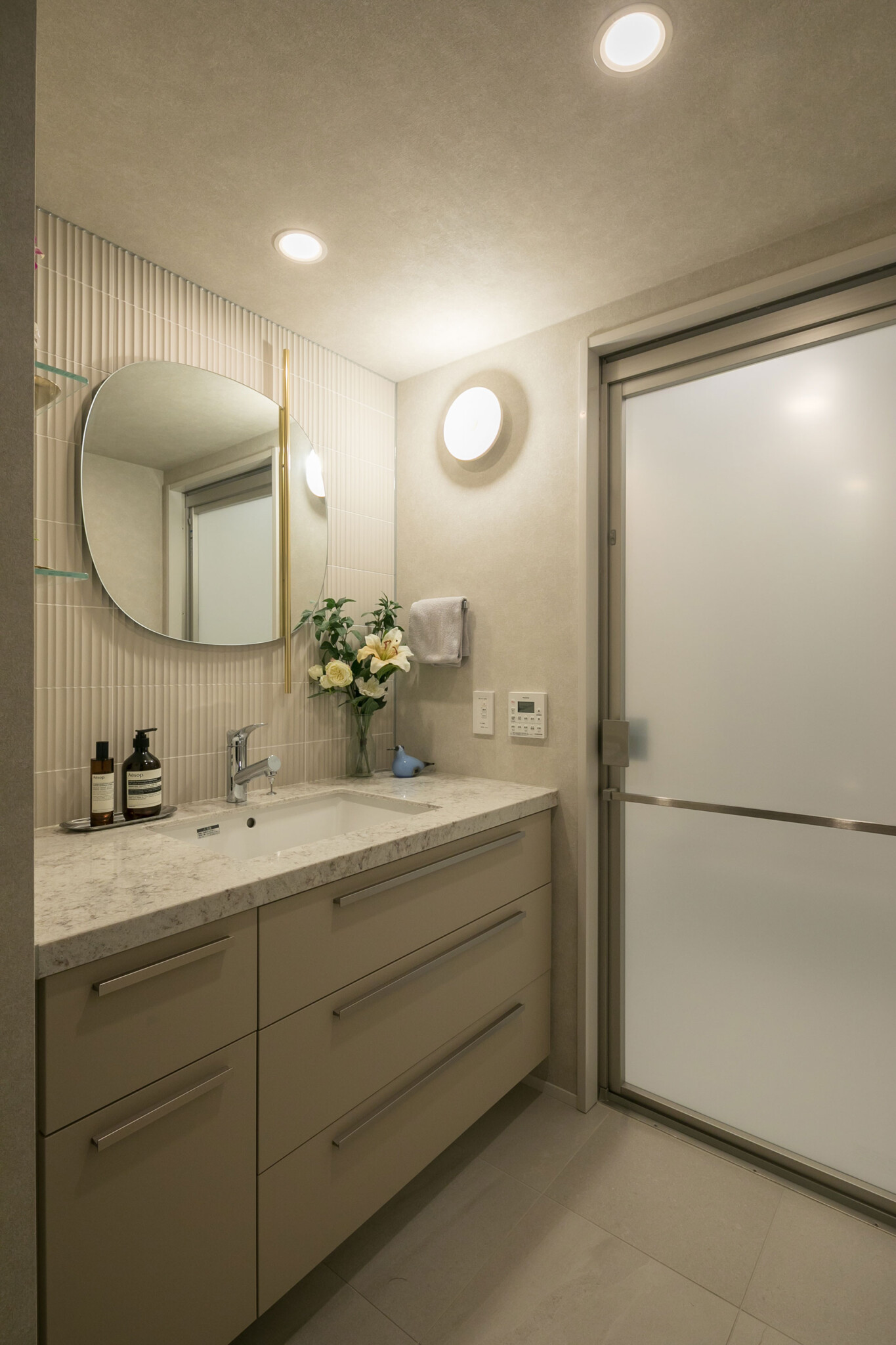 洗面の壁面をタイル張りに変更して、鏡や照明を新たに設けている。