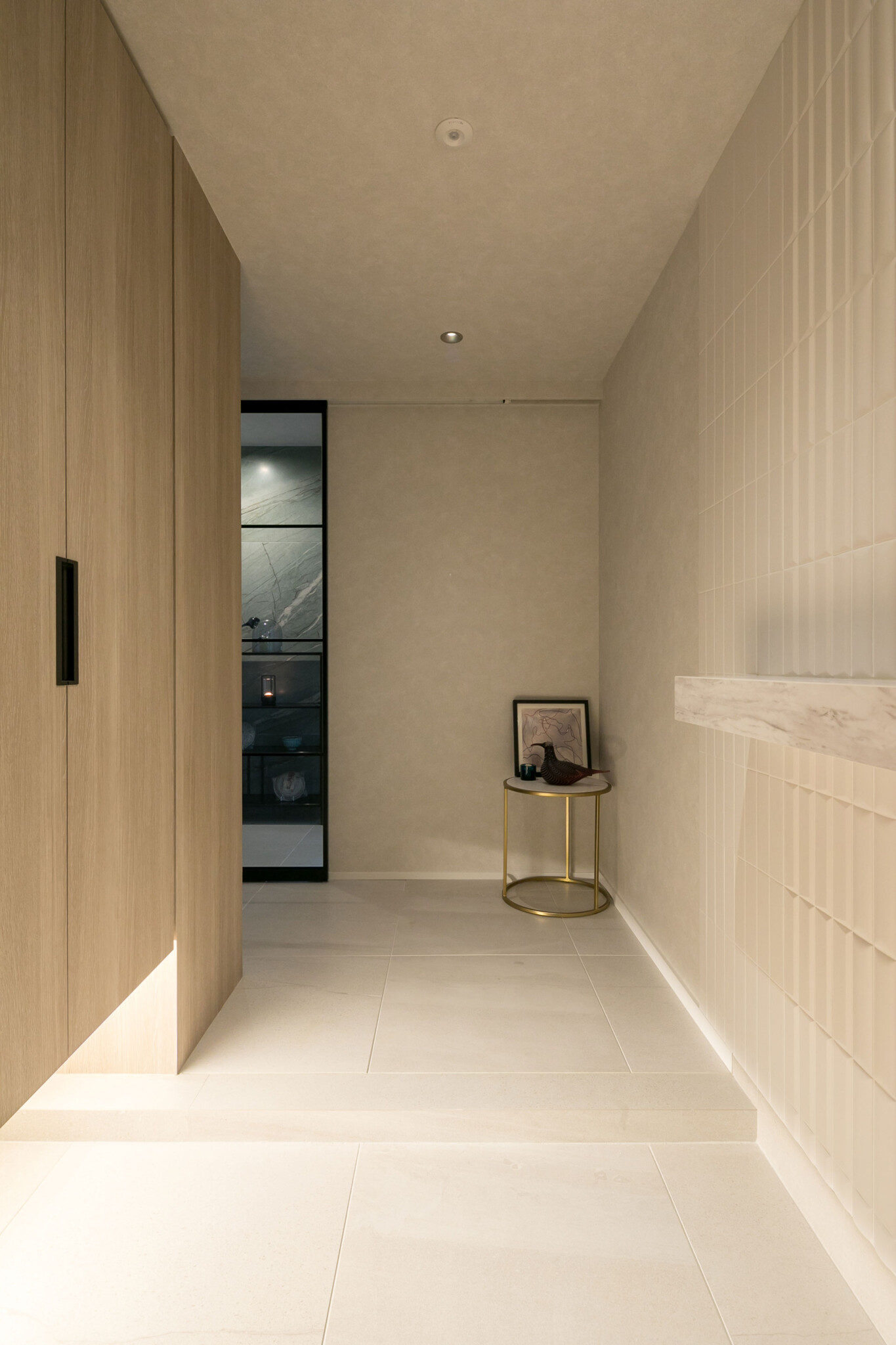 玄関ドアを開けると、白とベージュでまとめられた空間の奥にホールが見える。