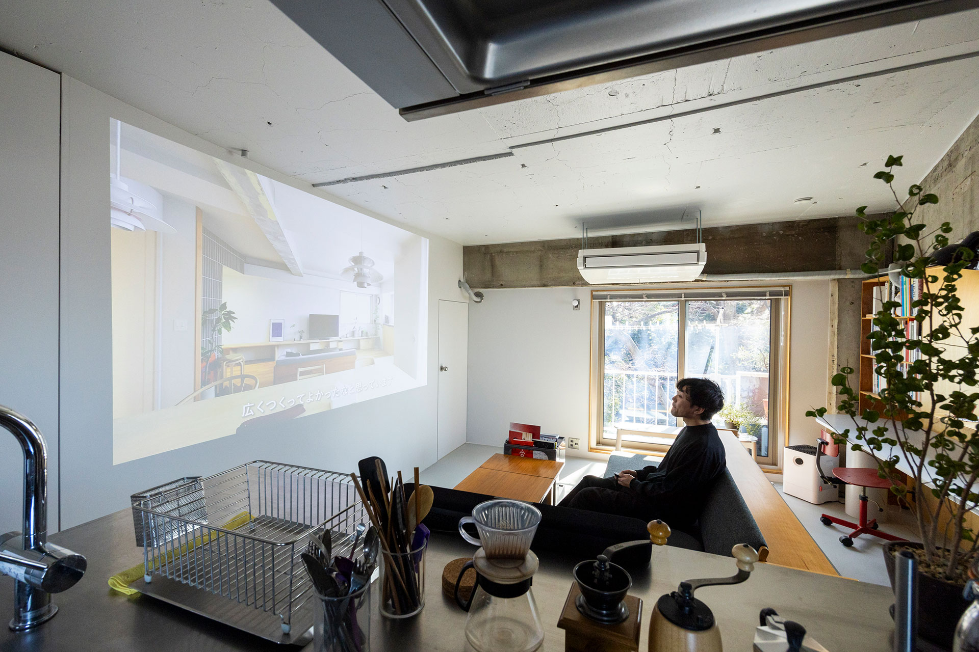 壁に写した大画面の映像を楽しむ。キッチンに立ちながら観ることも。