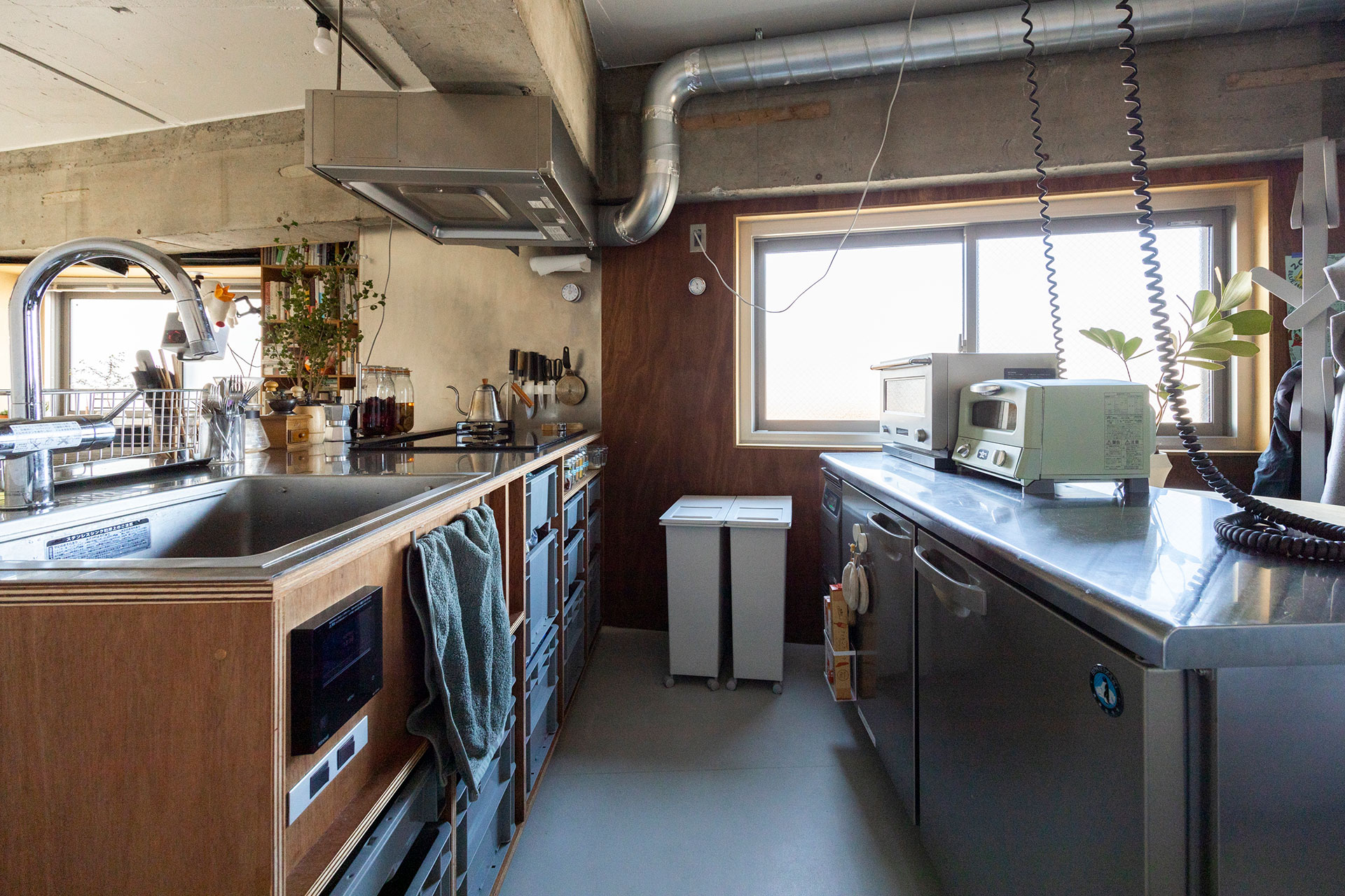 アイランドと高さを揃えた業務用の冷蔵庫は、ホシザキのもの。作業台としても便利。キッチン台の天板、レンジフードはステンレスのバイブレーション仕上げ。