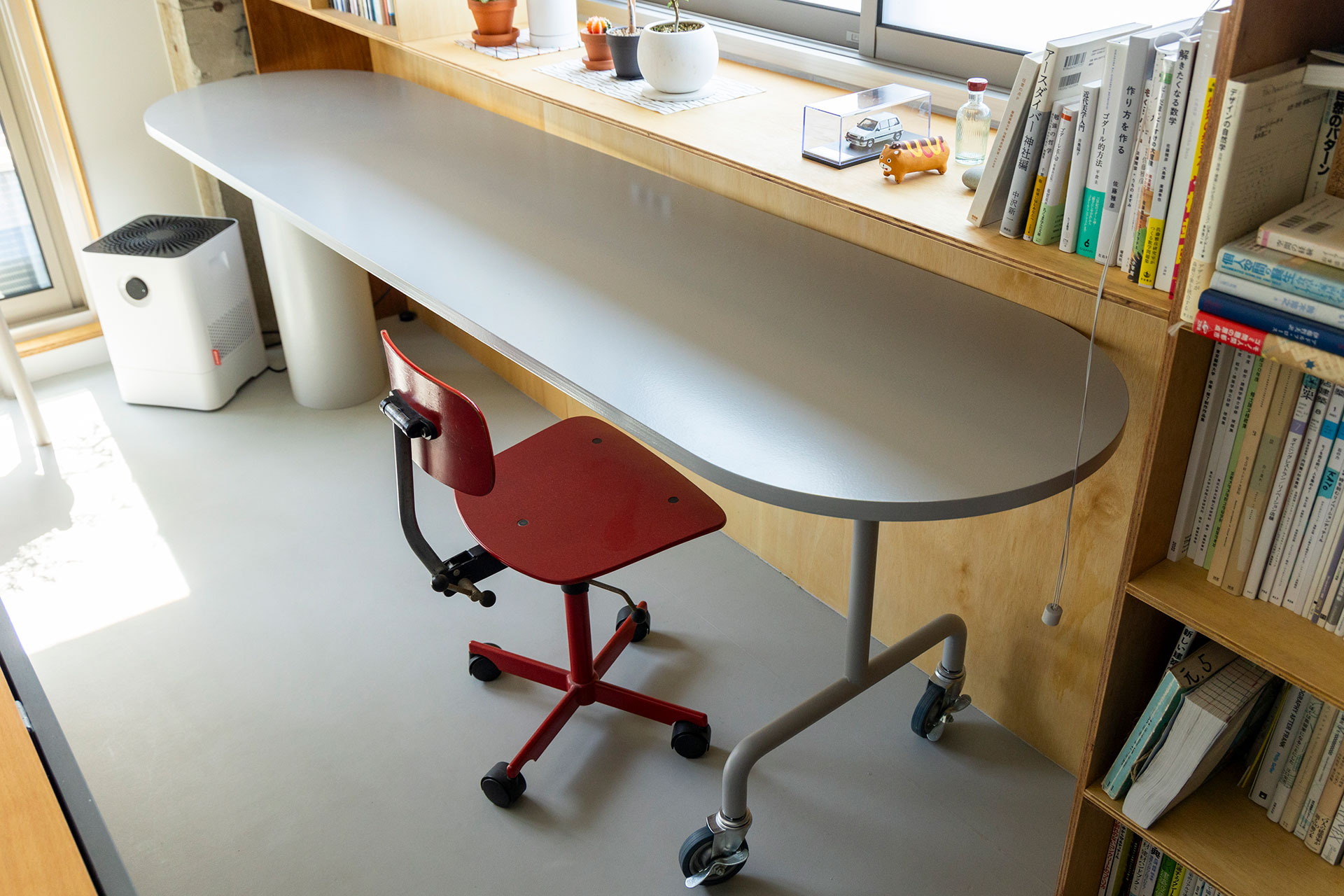 金物屋にオーダーしたキャスター付きの脚と、紙管メーカーを当たって見つけた管を脚にしてDIYしたテーブル。赤いヴィンテージのイスはヨルゲン・ラスムッセンのKEVI Chair。本棚もすべて造作した。
