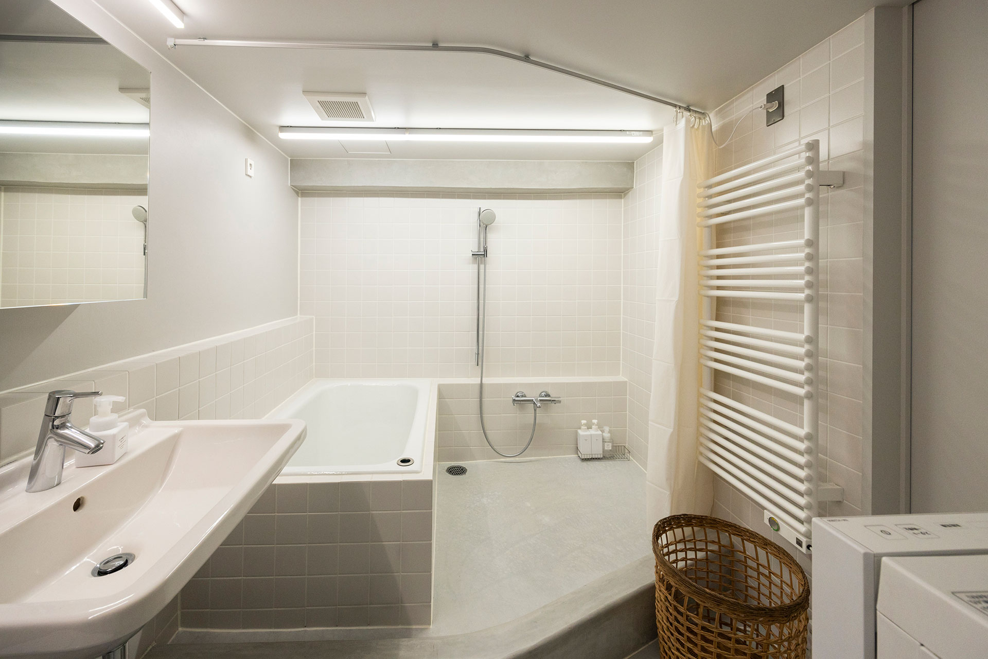 屋外用の防湿型LEDベースライトが使われた明るくクリーンな水廻り。洗い場にはモルタルを敷き、屋外用の防水塗料を塗った。タオルウォーマーは湿気を緩和する上、冬場は暖かくておすすめ。