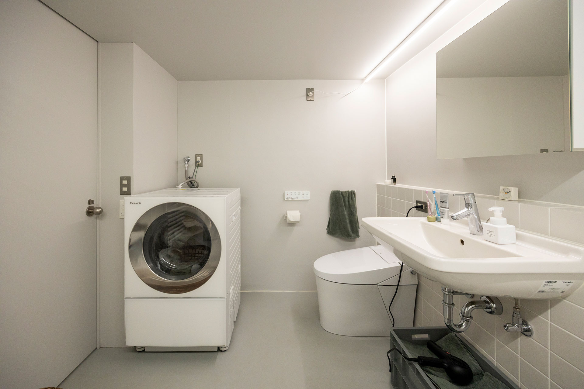 シンプルで機能的な空間。お風呂からトイレまで一面の壁に使ったマットなライトグレーのタイルが、一体感を生んでいる。