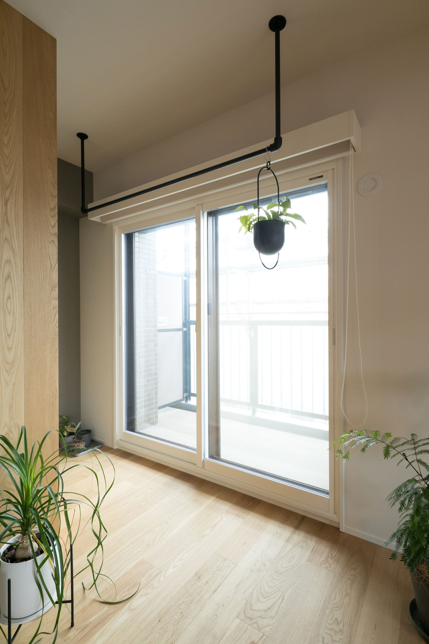 リビングの窓側から壁の裏に回ると、収納スペースがある。窓の前にはハンガーポールを設置した。