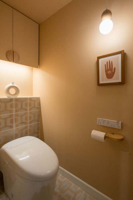 トイレには柄のタイルを張り、壁はテラコッタピンクに塗って個性的な空間に。収納棚には間接照明を入れている。