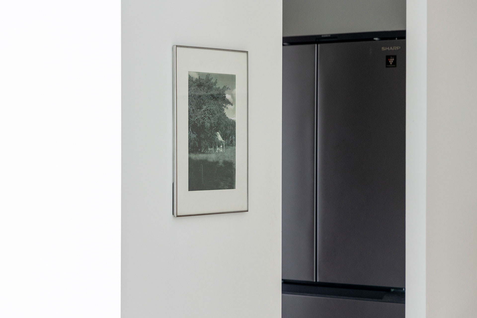 家電はパントリーで目隠し。冷蔵庫もマットなシルバーに。お気に入りの写真家の作品を、写真集からコピーして額装している。